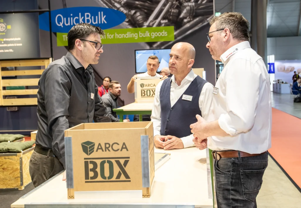 Besucher im Gespräch am ARCA-Messestand mit einer ARCA Box