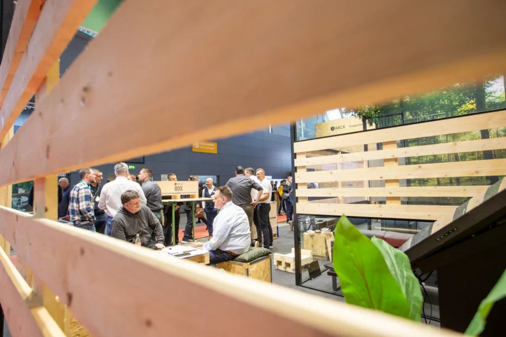 Blick durch die Holzgestaltung auf Gespräche am ARCA-Messestand